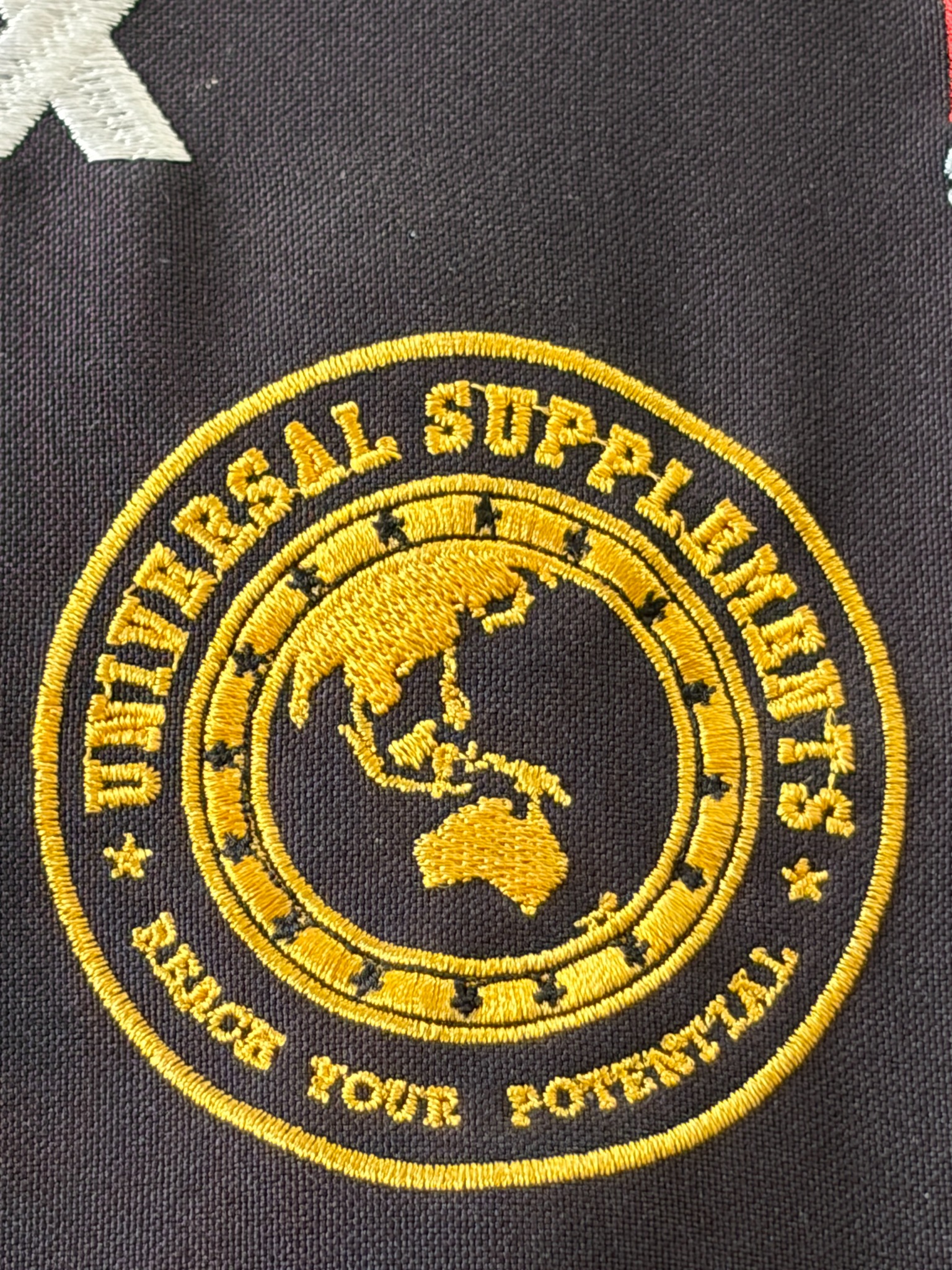 Gold Universal Suppliers football emblem on black fabric