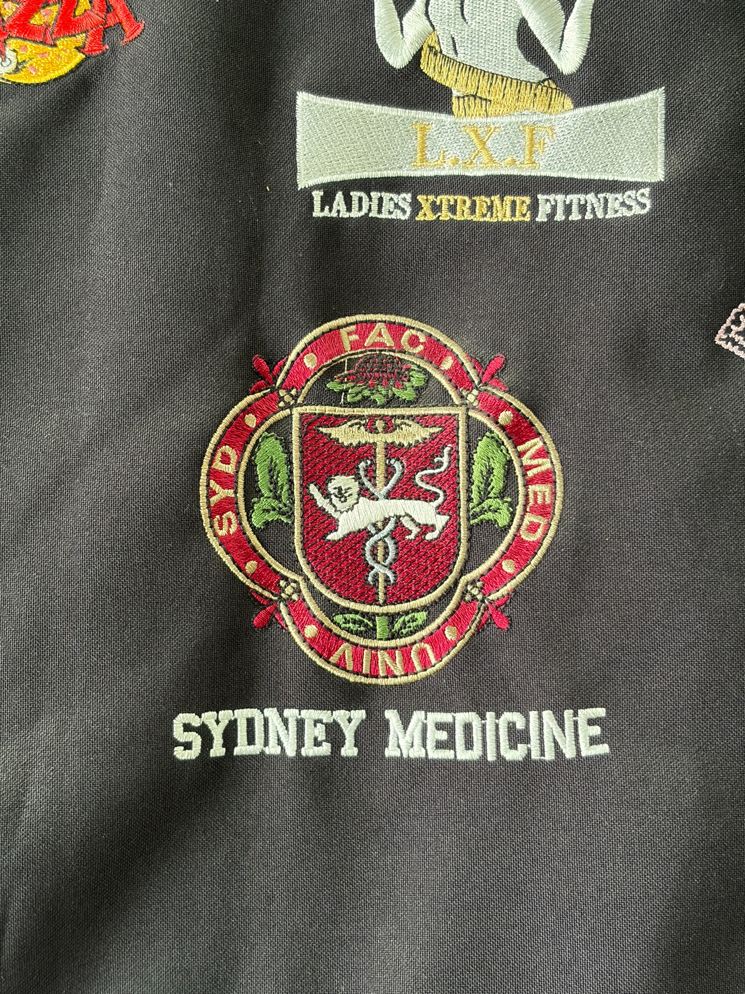 Sydney Medicine crest embroidered on dark fabric